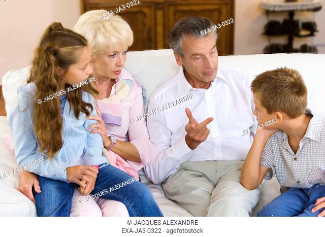 Grandparents talking to grandchildren on sofa
