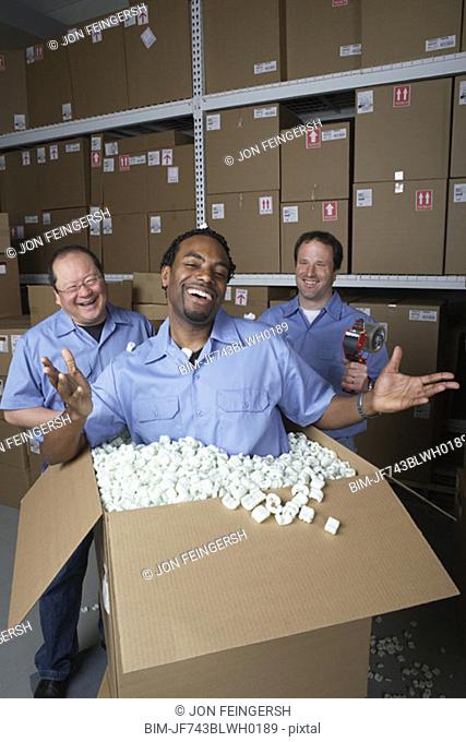 Three male warehouse workers joking around