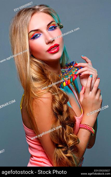 Closeup portrait of beautiful young woman with bright colorful makeup and matching neclace. Emotions. Over grey background