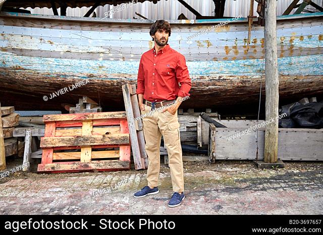 Young man walking in shipyard, ship in the port of Pasaia, Gipuzkoa, Basque Country, Spain, Europe