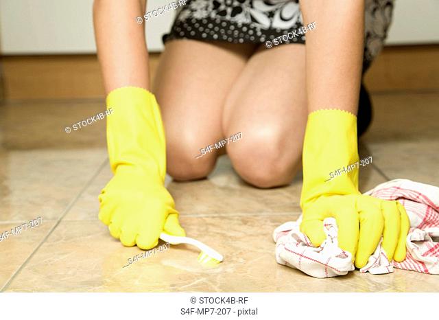Woman cleaning floor with toothbrush, Germany