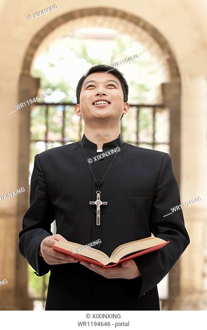 Young Priest Looking to Sky in Front of Doorway