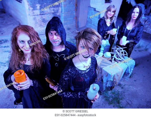 Coven of smiling witches outdoors holding candles