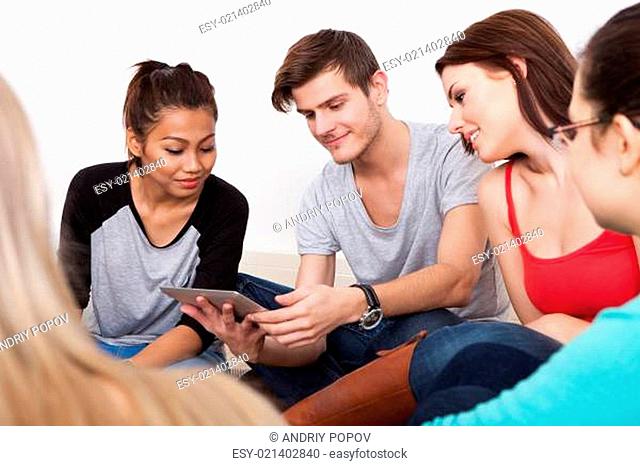 Group of university students using digital tablet on floor