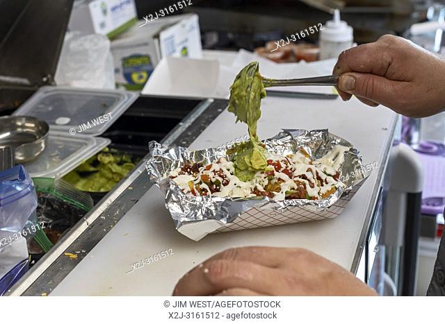 Golden, Colorado - Adam Hjermstad adds guacamole to a dish in his Fire in the Hatch food truck, where he serves green chili and other Colorado-inspired dishes