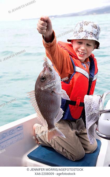 A young boy who has just caught a fish