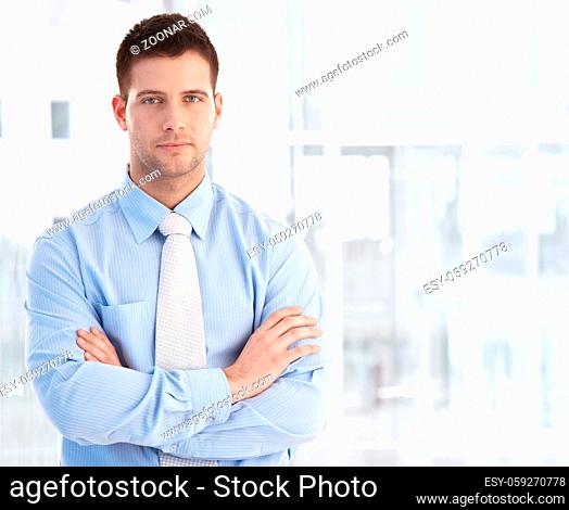 Handsome young businessman standing arms crossed