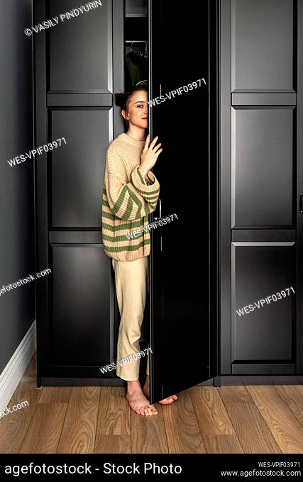 Woman standing by closet door at home