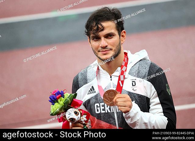 03 September 2021, Japan, Tokio: Paralympics: Athletics, men's 200 metres, T61, final, at the Olympic Stadium. Ali Lacin from Germany holds up his bronze medal...