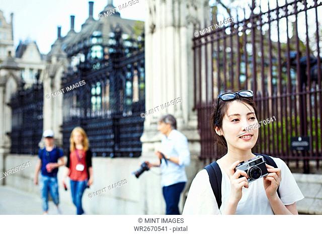 Young Japanese woman enjoying a day out in London, holing a camera