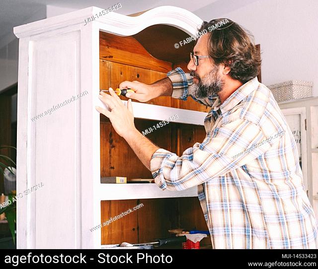 Adult man at home restoring and painting old furniture. Recycling and renewing for circolar sustainable economy lifestyle