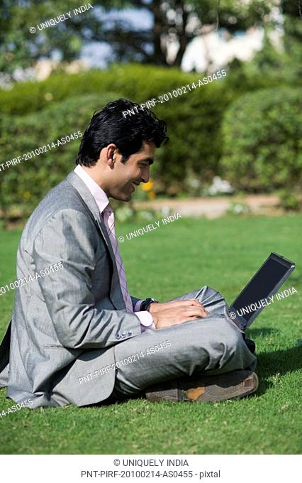 Businessman working on a laptop in a park, Gurgaon, Haryana, India