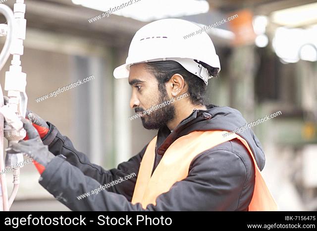 Technician with beard and helmet works in a workshop, Freiburg, Baden-Württemberg, Germany, Europe