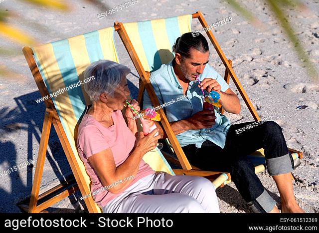Senior Caucasian couple sitting on deck chairs at the beach