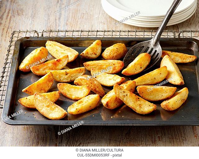 Seasoned potato wedges. Seasoned with salt and pepper on baking tray and wire rack