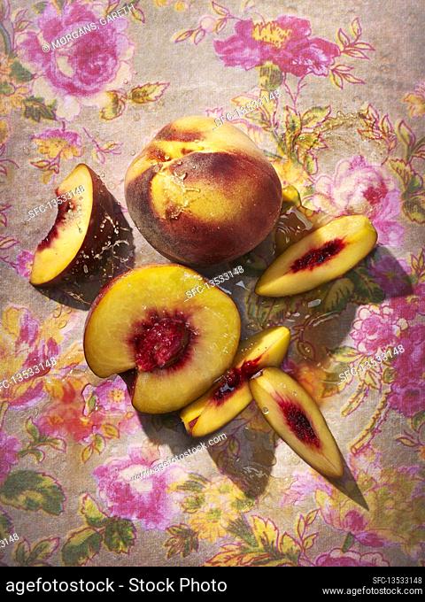 Fresh peaches, whole and sliced on a floral background