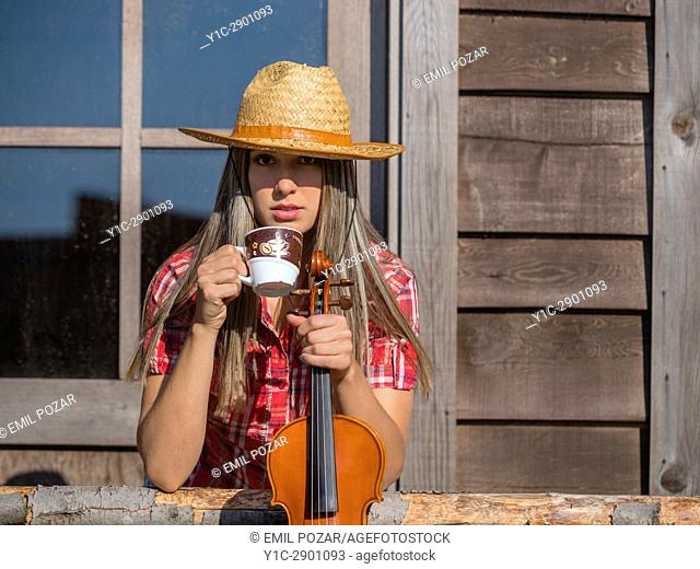 Country-girl countrygirl drinking coffee and violin in hands in wild west environment. Croatia