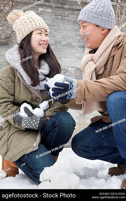 Couple Holding snow balls in park