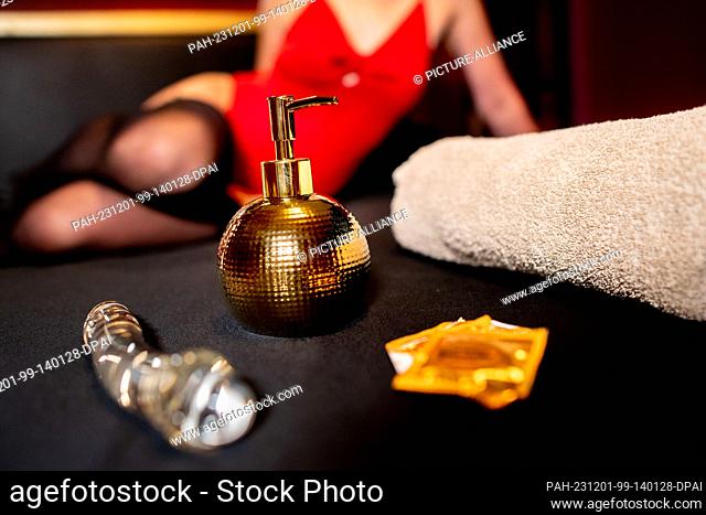ILLUSTRATION - 16 November 2023, Lower Saxony, Oldenburg: A dildo, a lubricant dispenser, condoms and a towel lie on a bed in a brothel