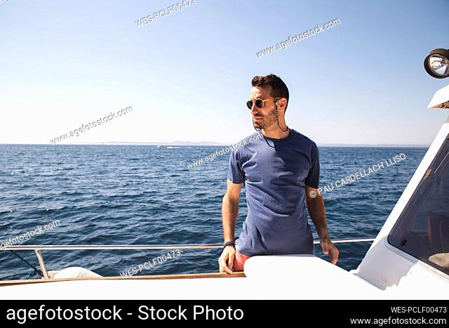 Man wearing sunglasses standing on yacht at sunny day