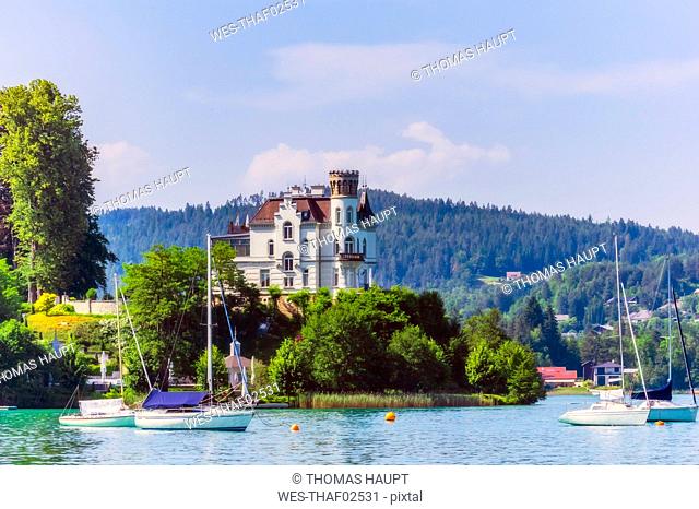 Sailboats moored at lake by church in Woerthersee against sky