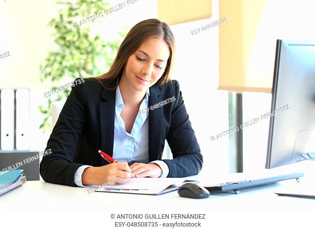 Busy businesswoman writing in an agenda on a desktop at office
