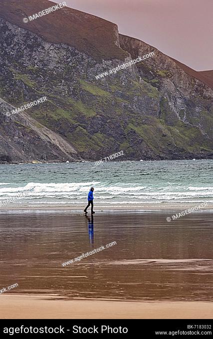 Walker walking along the beach in the evening, Keel beach, Acaill, Achill Island, Mayo, Wild Atlantic Way, Ireland, Europe