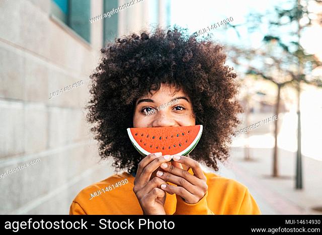 one happy and beauty cheerful woman holding a small watermelon covering her mouth. African or American girl having fun and enjoying