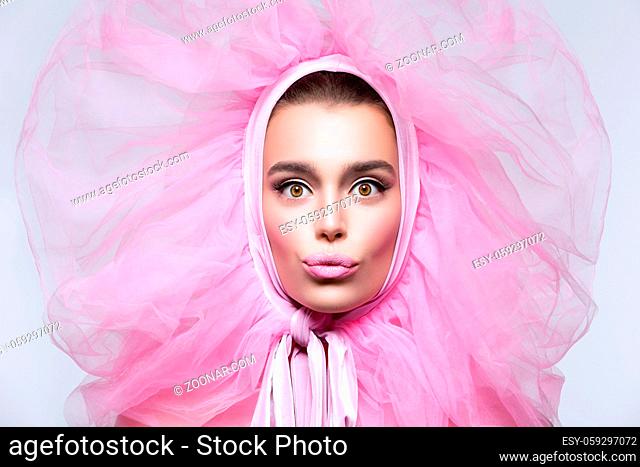 Beautiful happy young woman in fluffy pink headwear with kissing expression. Beauty shot. Over grey background