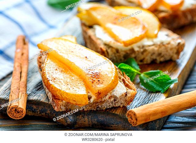 Toast with ricotta, pear and cinnamon on a wooden stand, selective focus