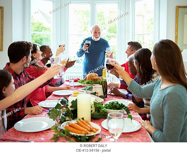 Grandfather making toast with wine at Christmas dinner table