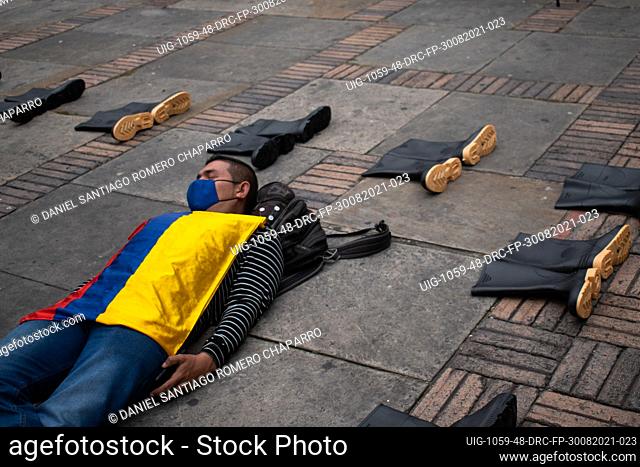 A men lays on the ground with a colombian flag as sets of rubber boots are set in the ground as flase positive victims were found with these on after being...