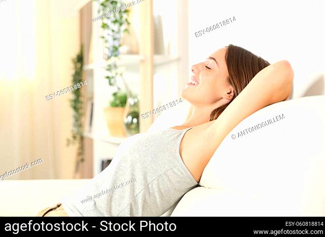 Side view portrait of a happy woman with waxed armpit relaxing sitting on a sofa in the living room at home