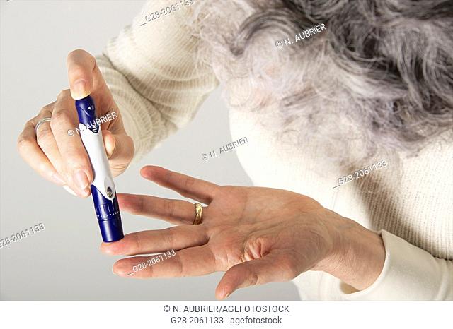 Close up of Senior woman' hands using a lancet for blood sugar testing for diabetes