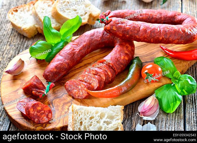 Spanische Spezialität: Luftgetrocknete scharfe Chorizo Paprikasalami auf Olivenholzbrett serviert ? Spanish salami: Spicy chorizo sausage with tomatoes and...