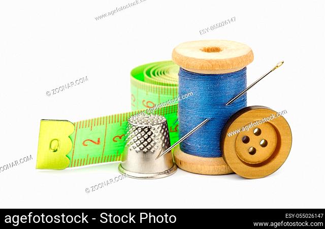 Spool of blue thread, needle, button, measuring tape and thimble isolated on white