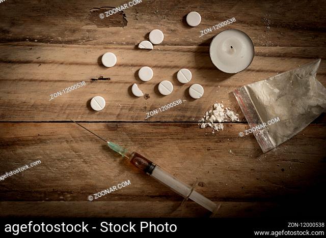 Drugs, powder, syringe and tablets on rustic wooden floor background. Drug addiction concept background with space for text