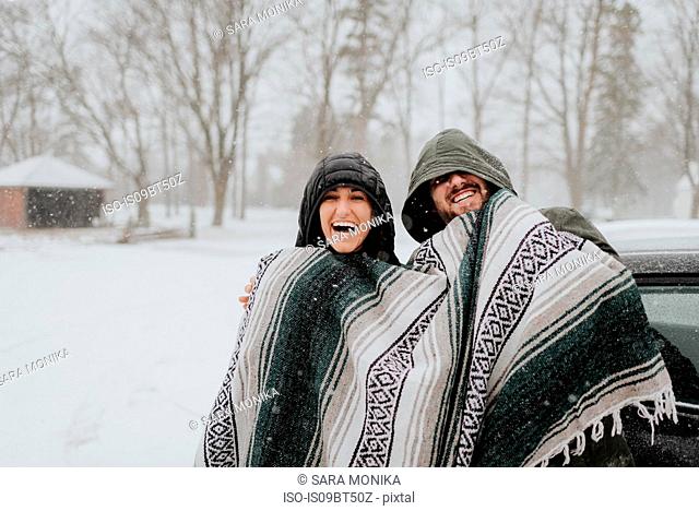 Couple wrapped in blanket in snowy landscape, Georgetown, Canada