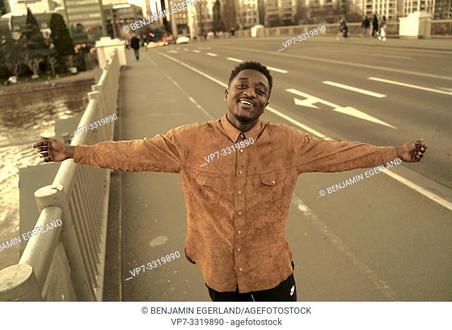 carefree African man with open arms at street in city, in Frankfurt, Germany