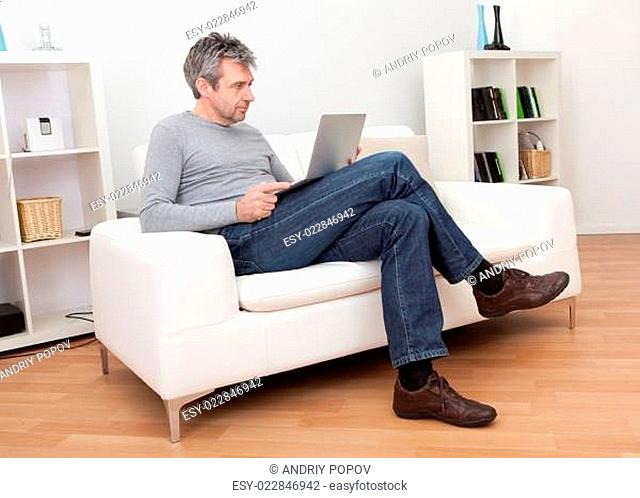Senior man sitting in sofa and using laptop