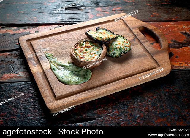 Delicious stuffed mushrooms with spinach and cheese isolated on rustic wooden background