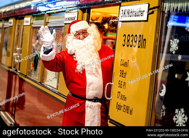 02 December 2023, Berlin: A man in a Santa Claus costume waves from the Christmas train of the Historische S-Bahn association