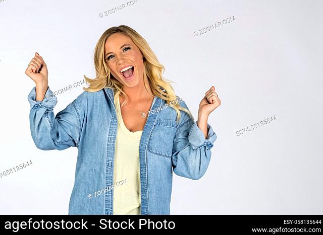 A gorgeous blonde model pointing and showing emotion while posing in a studio environment