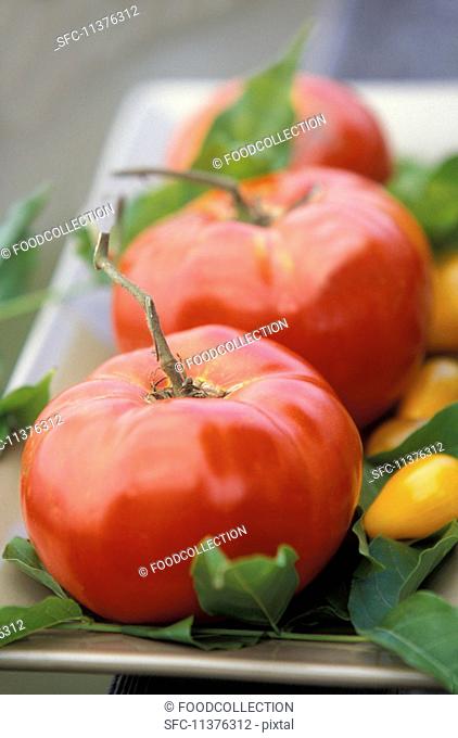 Beefsteak tomatoes and yellow pear tomatoes on a serving platter