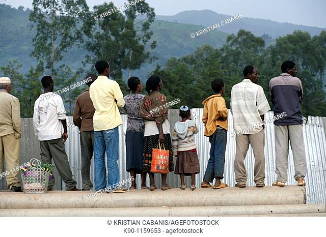 People, seen from behind, standing at a metal barrier and looking over it, Mizan Tefari, Ethiopia, East Africa
