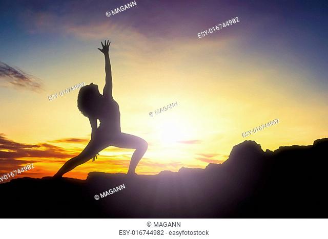An image of a pretty woman doing yoga at sunrise