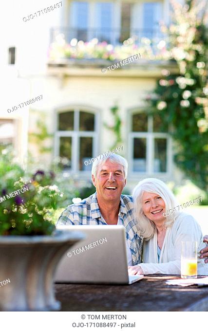 Senior couple using laptop at table in garden