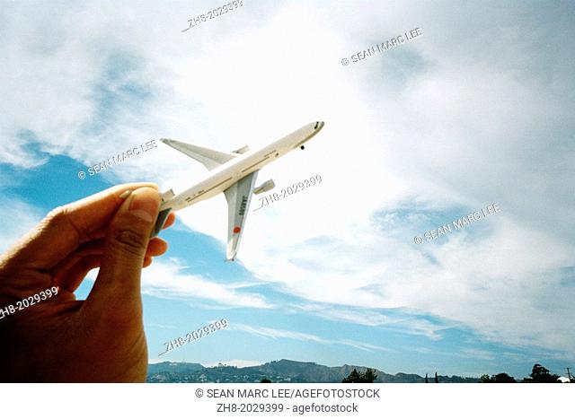 A toy airplane held over the bright blue sky