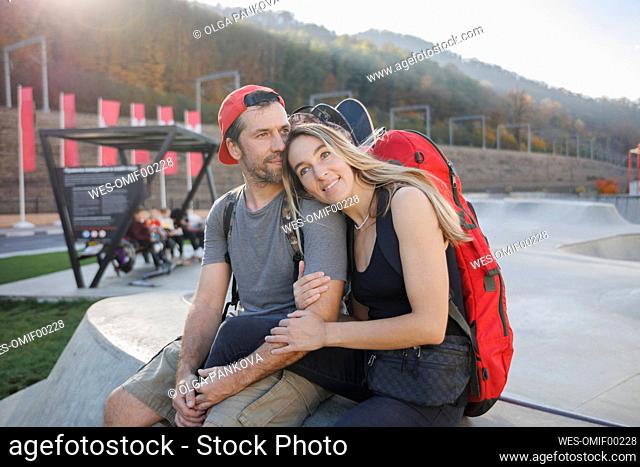 Man sitting with woman on concrete wall at skatepark