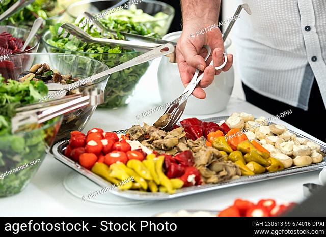 SYMBOL - 12 May 2023, Baden-Württemberg, Rottweil: A man helps himself to appetizers from a buffet during a corporate event. Photo: Silas Stein/dpa